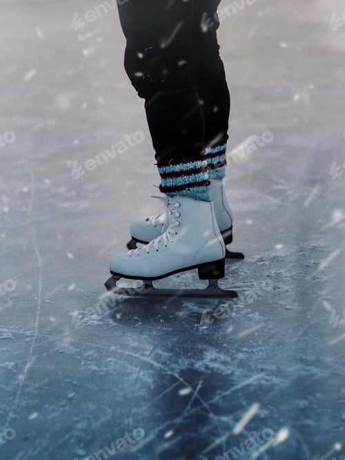 Preview: Vertical closeup of a person in white skates on the ice during the snowfall