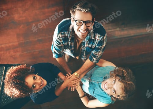 Preview: Portrait of a group of designers joining their hands together in a huddle