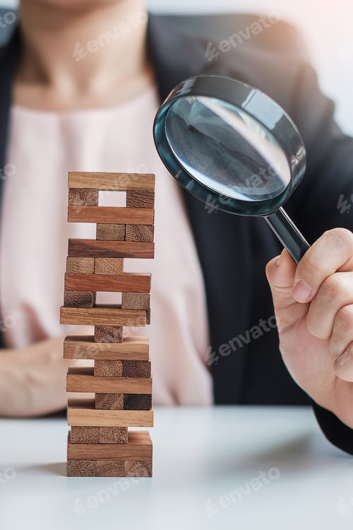 Preview: Businesswoman hand holding glass magnifying over wooden blocks tower. Business analysis, Risk