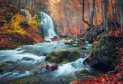 Preview: Waterfall at mountain river in autumn forest at sunset.