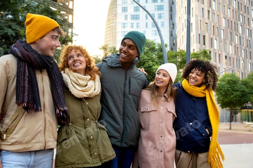 Preview: Happy multiracial friends laughing embracing together while walking around city on a winter day