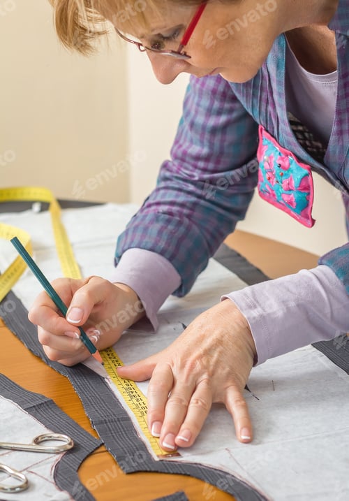 Preview: Dressmaker drawing tailor pattern on the table