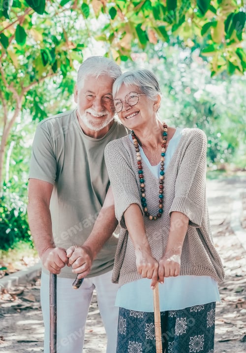 Preview: Cheerful senior couple walking in the park with help of a walking cane