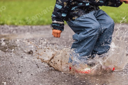 Preview: Closeup of a kid stepping in the puddle on a rainy day