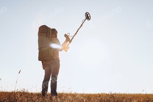Preview: Man with metal detector equipment searching for metal goods in the field