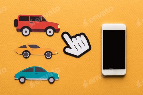 Preview: top view of paper cut cars, pointing hand and smartphone on orange background