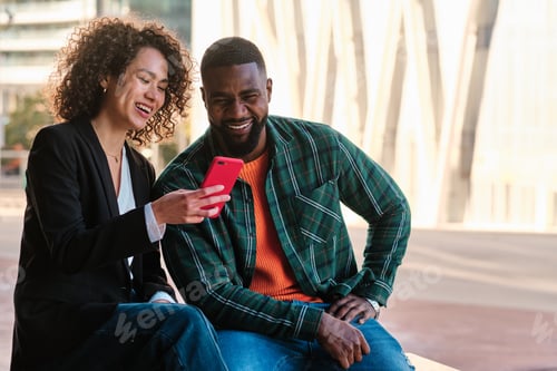 Preview: African friends using a mobile sitting on the street