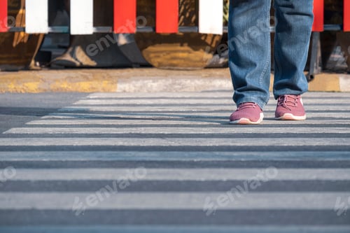 Preview: Front view of human legs walking across the street on zebra crossing in public area
