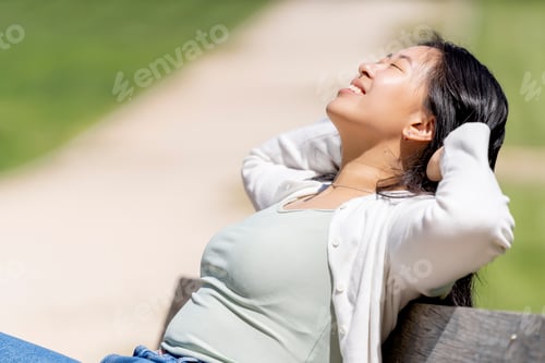 Preview: Asian happy woman resting on a seat in a park or forest