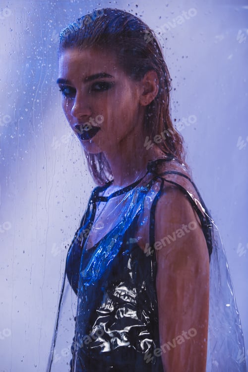 Preview: Fashionable model with wet hair and dark lipstick dressed in black swimming suit and transparent