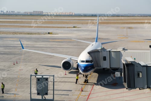 Preview: Plane docking at the airport gate with crew preparing for passenger boarding on a sunny afternoon