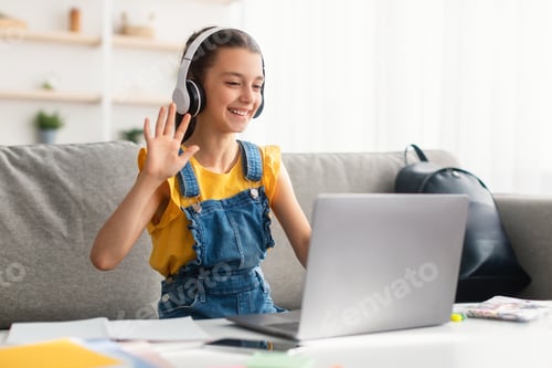 Preview: Cheerful girl sitting at table, using laptop, waving to webcam