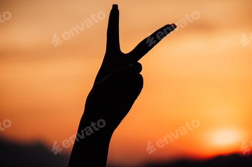 Preview: Silhouette of a hand doing a peace sign on an orange sunset background