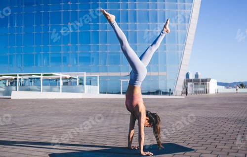 Preview: Calm woman in active wear enjoying recreation during yoga activity at urban setting,