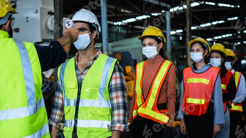 Preview: Industrial worker and engineer stand in line to check flu with infrared thermometer and manager