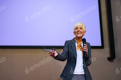 Preview: A smiling woman giving a speech at the conference, elegantly dressed.