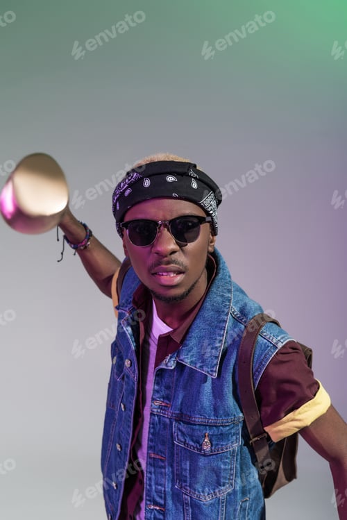Preview: aggressive young african american man in sunglasses holding golden golf club and looking at camera