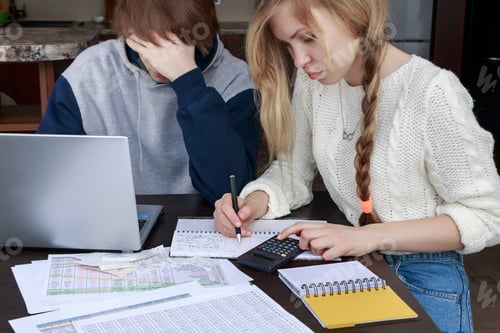 Preview: students at their desk perform calculations on a calculator and computer