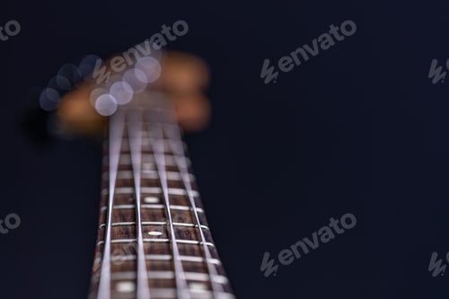 Preview: Close-up of a bass guitar fretboard on a blurred dark background.