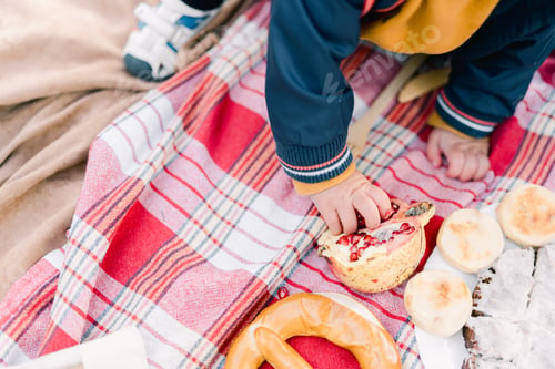 Preview: Small child picks out seeds from a pomegranate on a bedspread. Cropped. Faceless