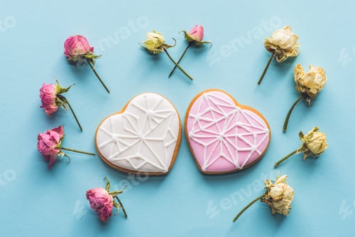 Preview: top view of heart shaped cookies and decorative flowers isolated on blue