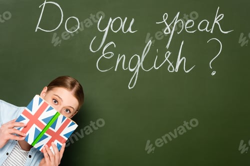 Preview: pretty girl with obscure face holding book with uk flag near chalkboard with do you speak English