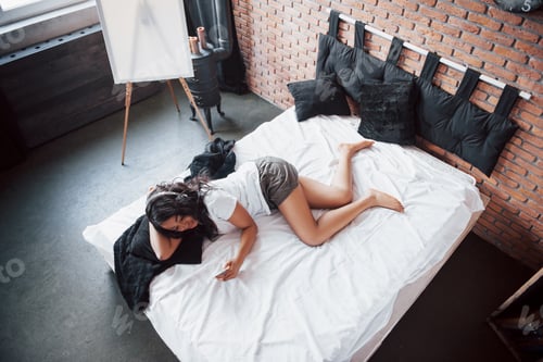 Preview: Portrait of beautiful woman waking up in her bed and looks into the phone