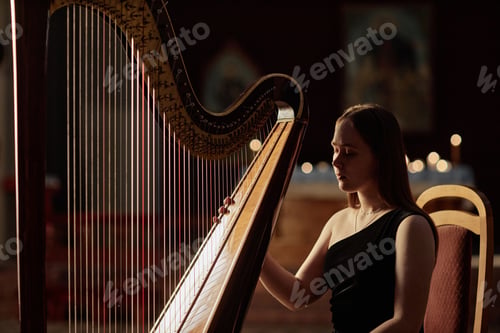 Preview: Woman Sitting at Harp Preparing to Perform Music in Church with Low Key Light