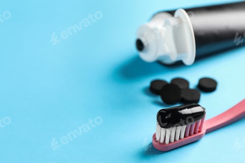 Preview: Brush with charcoal toothpaste on light blue background. Space for text