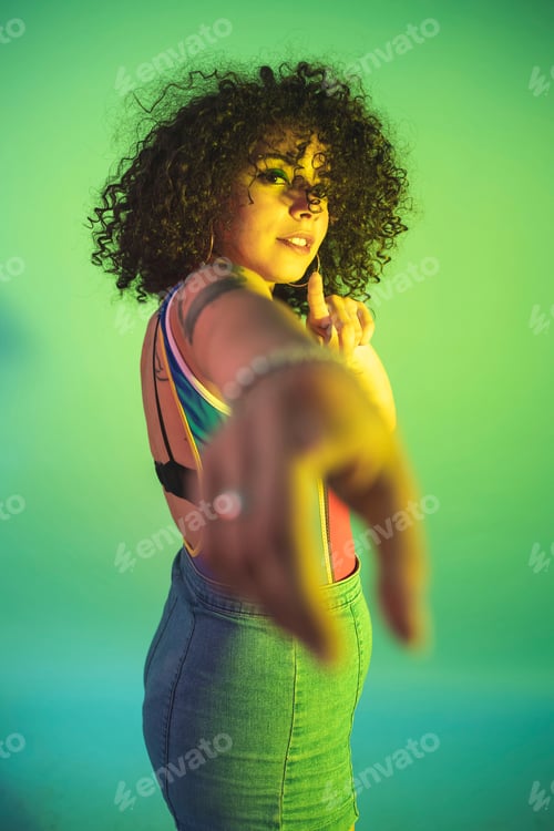 Preview: Woman with a playful pose and vibrant style against a green backdrop