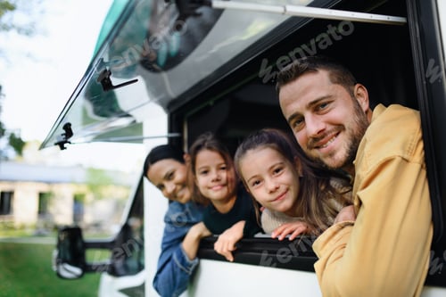 Preview: Happy young family with two children looking out of caravan window