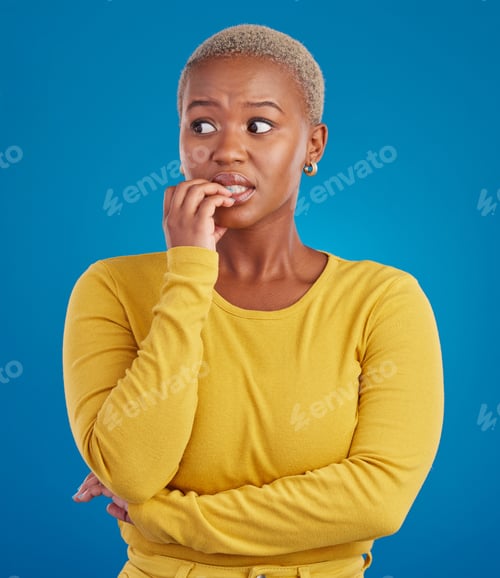 Vista previa: Nervous, worried and scared black woman in fear and bitting nails isolated against a studio blue ba