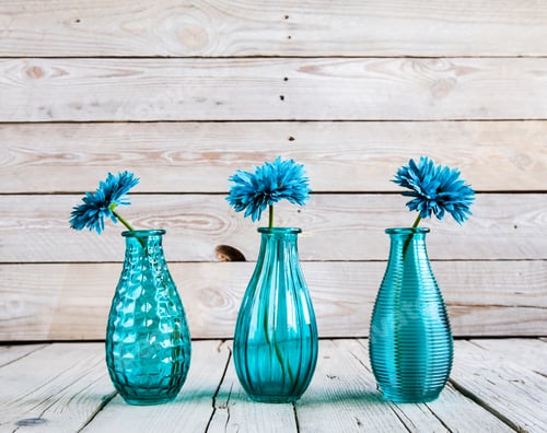 Vista previa: blue gerbera flower in a vase on wooden background