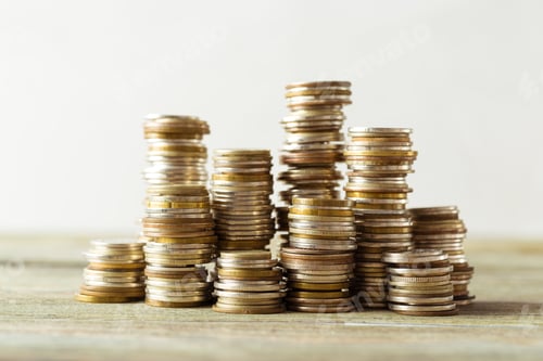 Preview: Stacks of coins arranged on a wooden surface during the daytime light