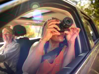 Preview: Passenger Taking Photo With Camera As Two Senior Female Friends Enjoy Day Trip Out In Car
