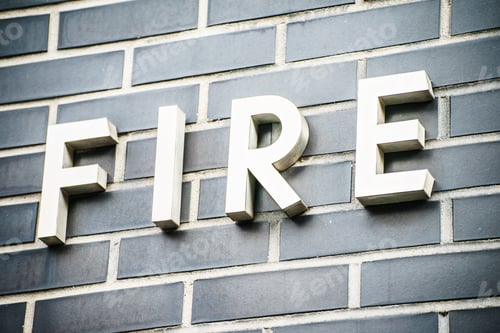 Preview: Closeup of a white sign saying fire on gray brick wall