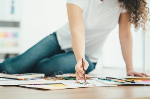 Preview: The woman sitting on the table and drawing on a paper.