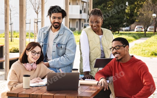 Preview: Cheerful millennial multiracial students look at computer, watch lesson, have video call, study