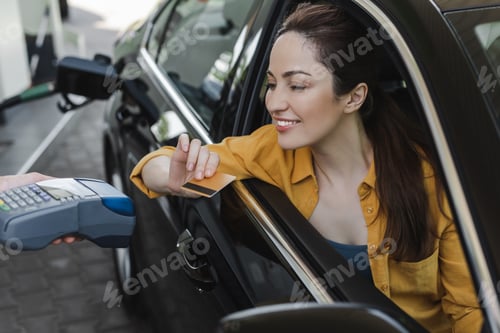 Preview: Selective focus of smiling woman holding credit in card near worker of gas station with payment