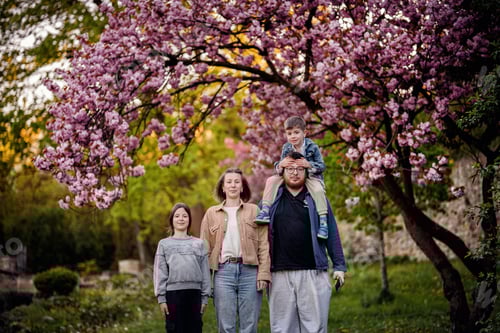 Preview: Happy Family Posing Under Blooming Cherry Blossom Tree