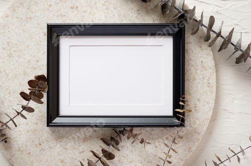 Preview: top view blank black photo frame mockup with eucalyptus brancch at peach wall