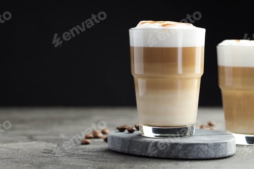 Preview: Tasty latte macchiato in glasses and coffee beans on grey table, closeup. Space for text