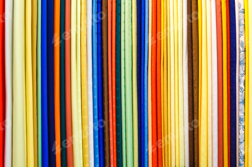 Preview: wide selection of different color textile silk fabrics clothes lay in row in drapery store
