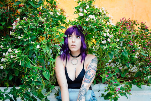 Preview: Thoughtful woman sitting alone outdoors. Young worried in backyard