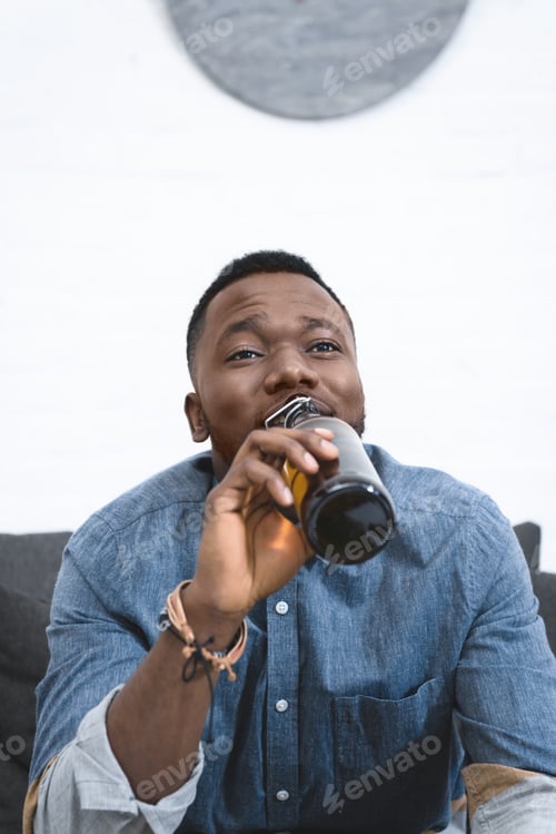 Preview: Young african american man drinking beer from bottle