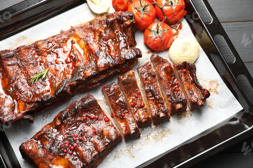 Preview: Delicious spare ribs, baked onion and sun dried tomatoes on grey wooden table, top view