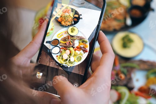 Preview: A person capturing a food plate with a smartphone, showcasing vi