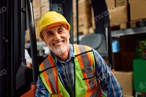 Preview: Happy senior forklift operator in a warehouse looking at camera.