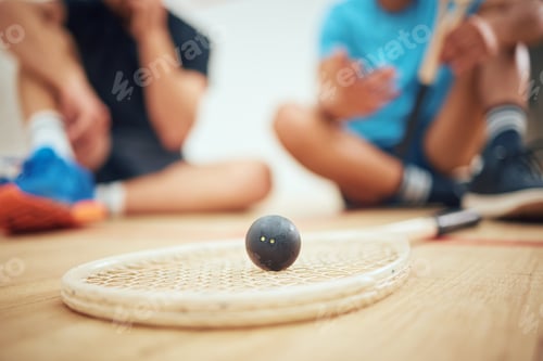 Preview: Closeup of squash equipment and gear on wooden floor in court with players in background at sports