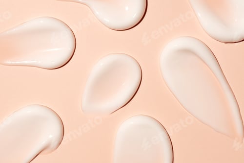 Preview: White cosmetic cream lotion swatch smears smudge on peach color background.